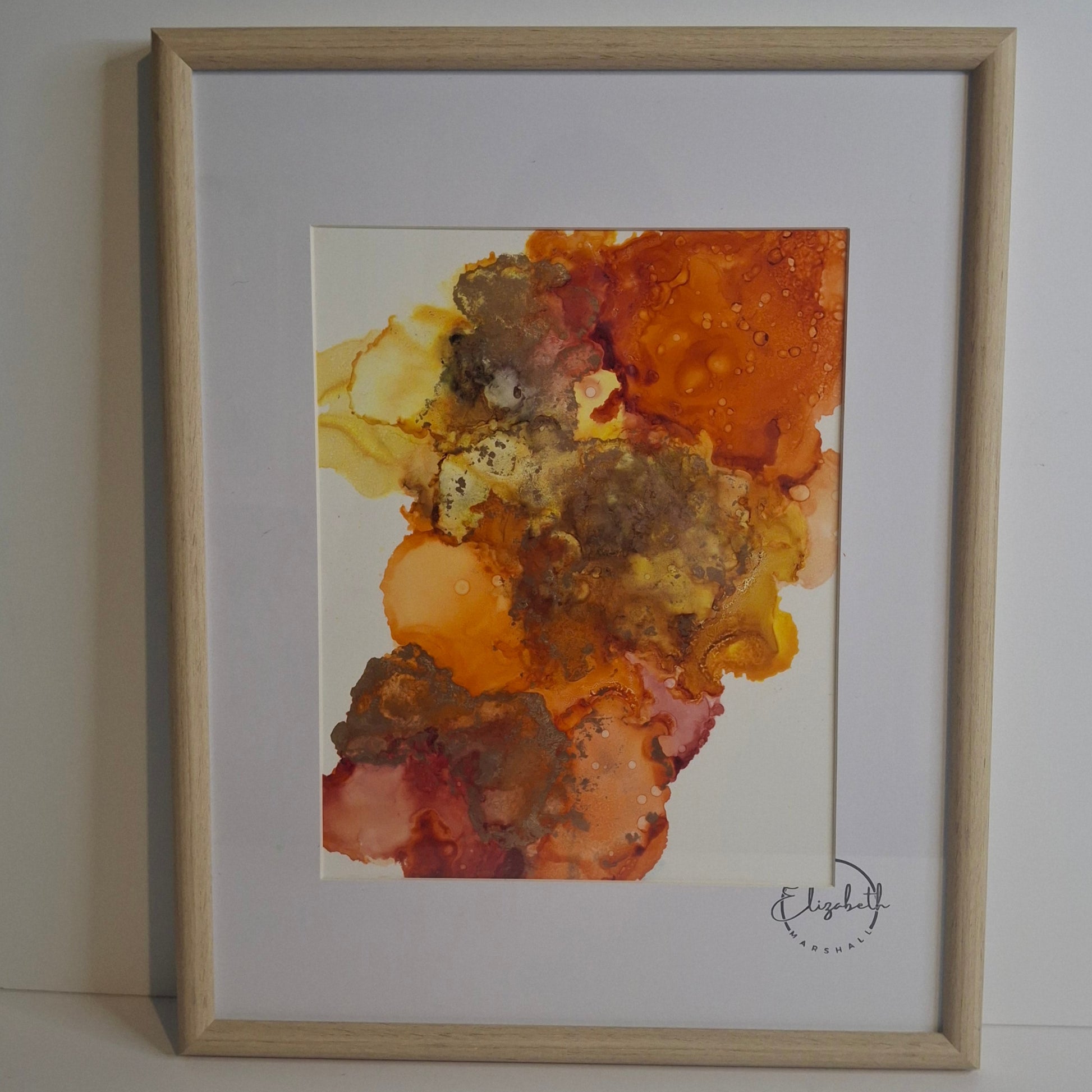 Framed abstract alcohol ink painting in warm golden amber and earthy rust tones titled Into the Light by Elizabeth Marshall.