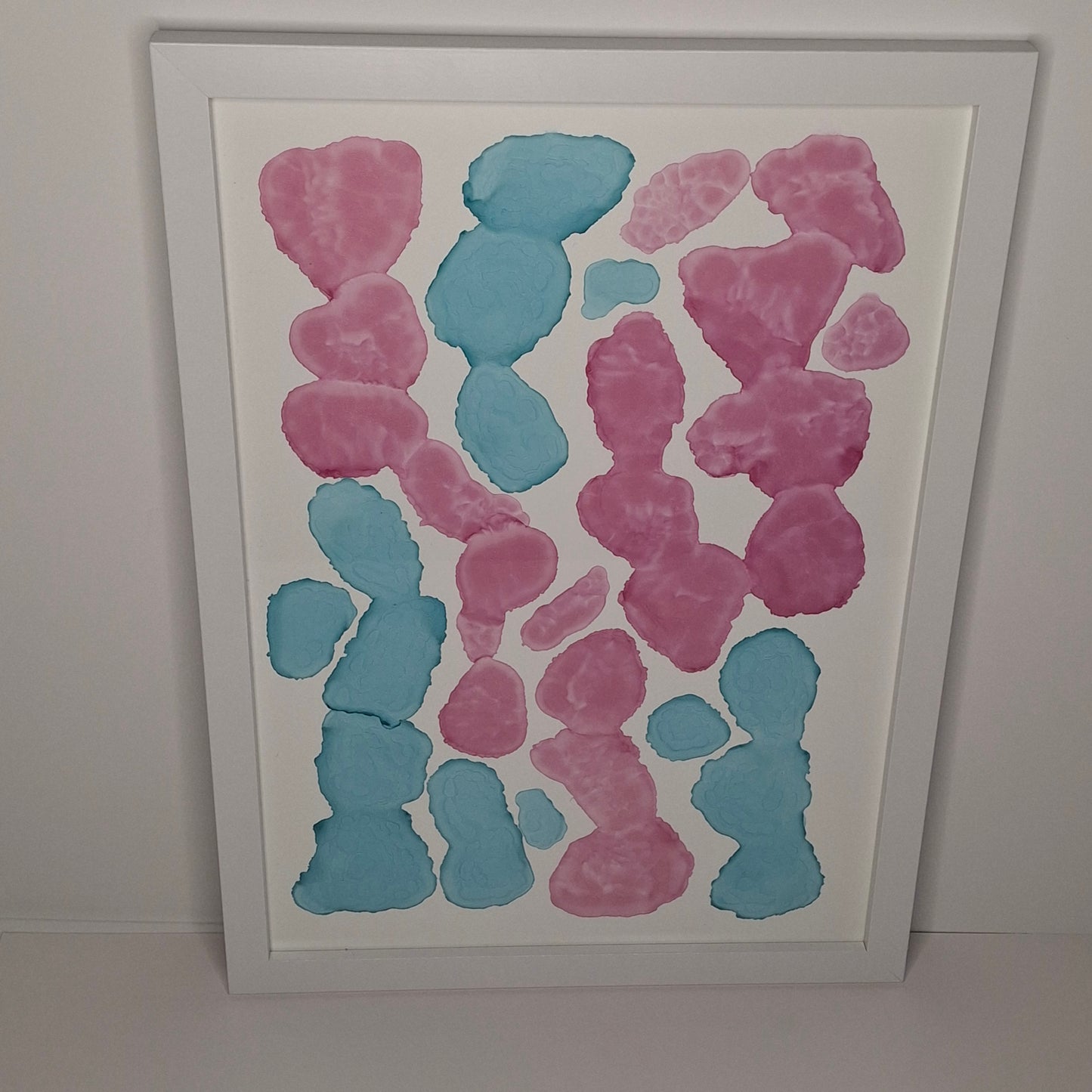 Framed artwork with pink and blue abstract shapes on a white background