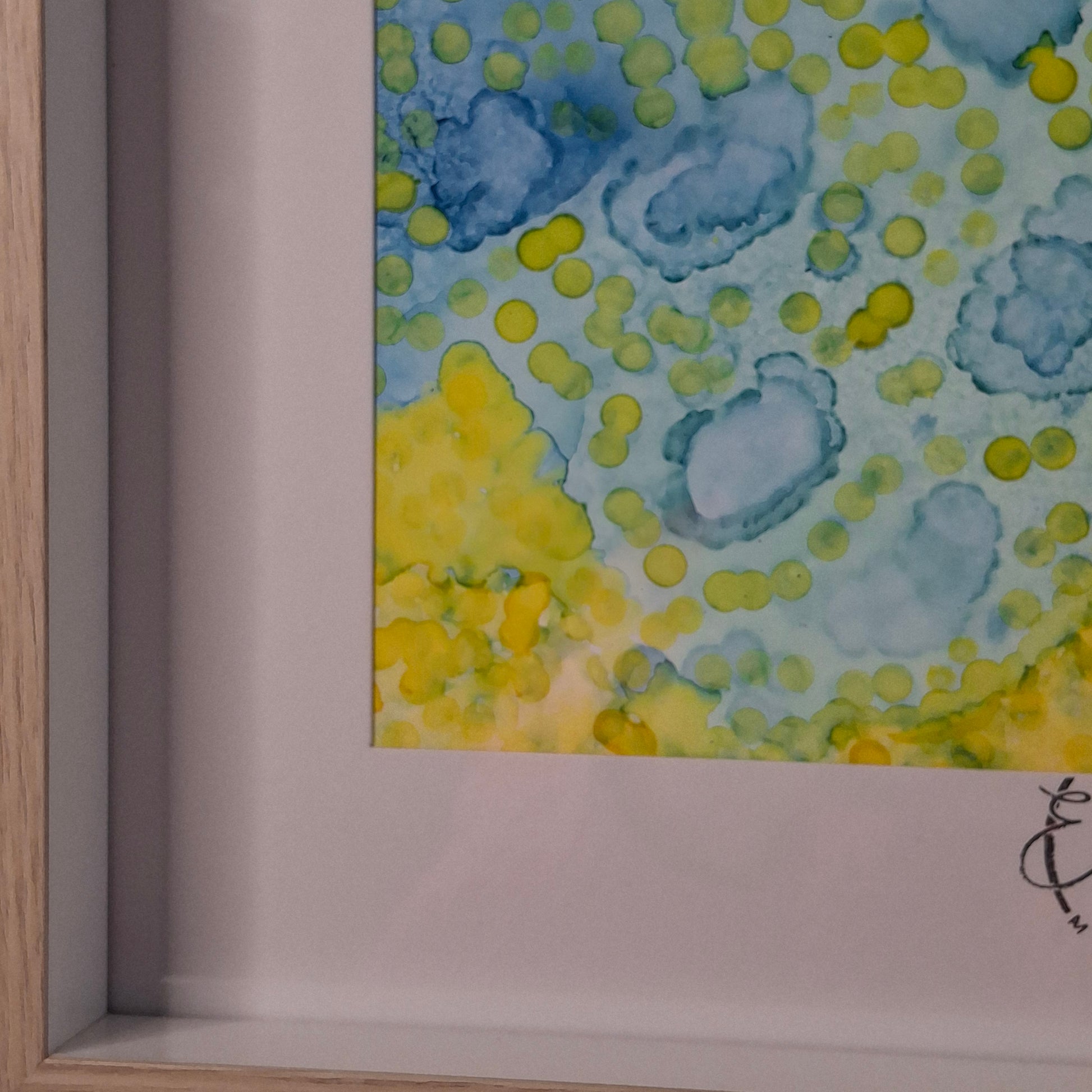 Close-up of a painting with blue and yellow abstract patterns on a white background.