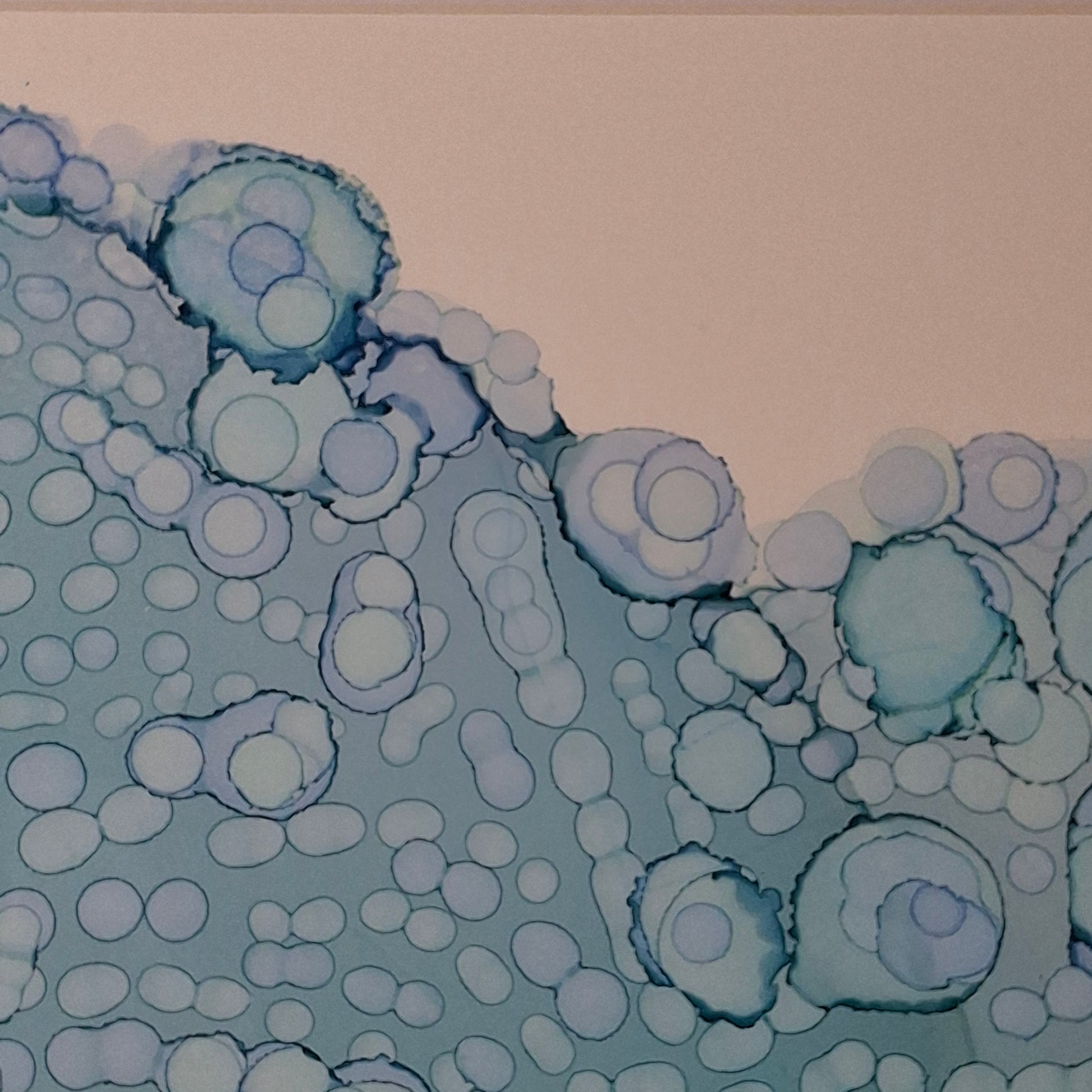 Framed blue alcohol ink artwork with overlapping bubbles and oceanic textures titled The Sea's Soft Embrace displayed in a coastal white kitchen