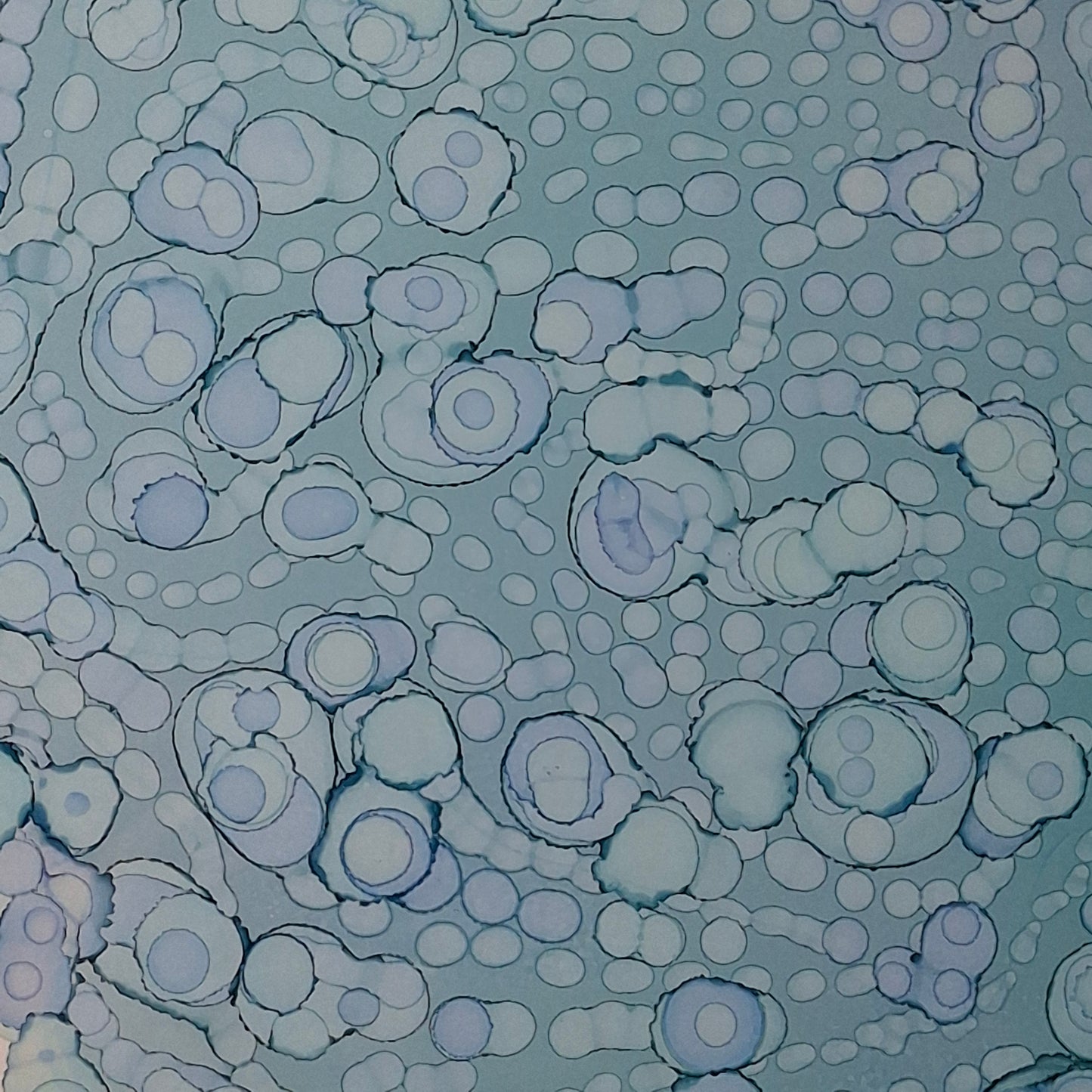 Framed blue alcohol ink artwork with overlapping bubbles and oceanic textures titled The Sea's Soft Embrace displayed in a coastal white kitchen