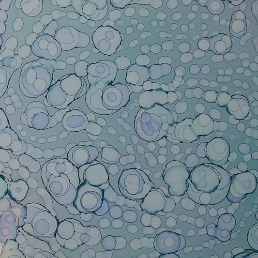 Framed blue alcohol ink artwork with overlapping bubbles and oceanic textures titled The Sea's Soft Embrace displayed in a coastal white kitchen