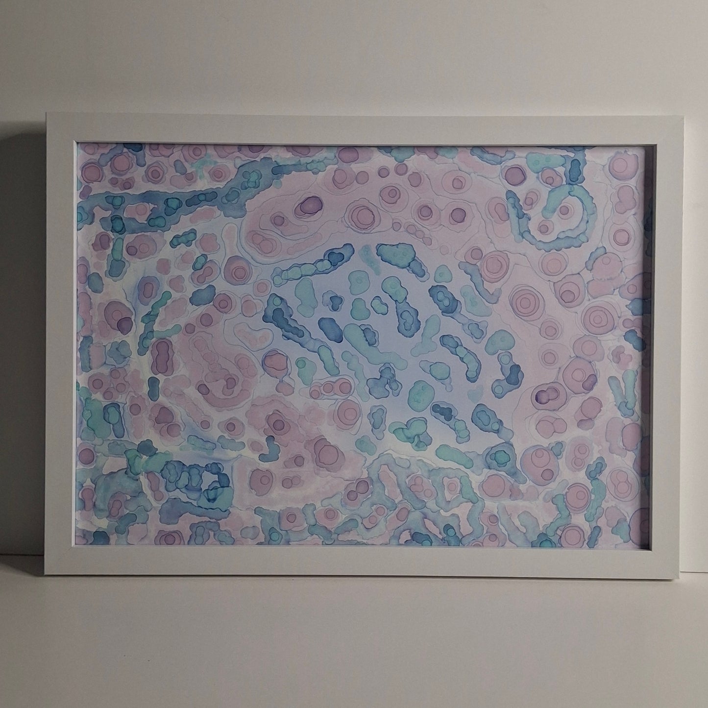 A framed A3 alcohol ink painting in soft purples, greens, and blues, titled "Moonlit Tide", inspired by ocean tides under moonlight.