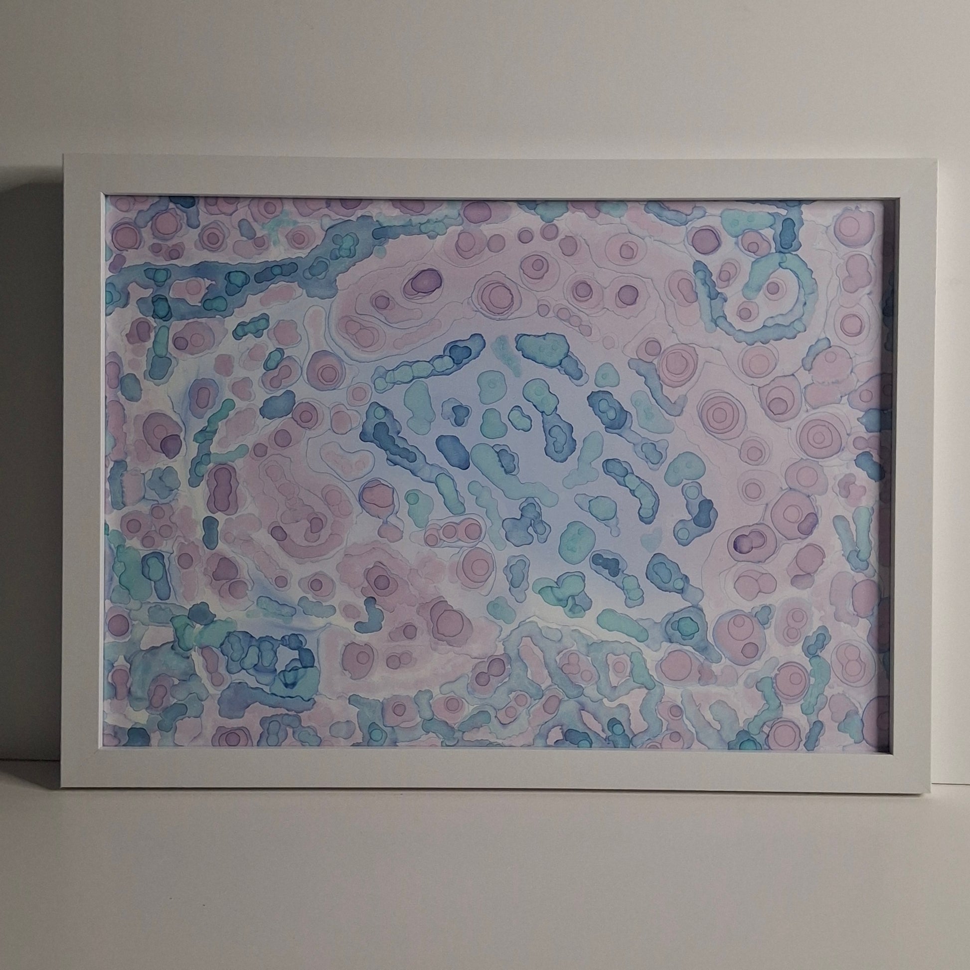 A framed A3 alcohol ink painting in soft purples, greens, and blues, titled "Moonlit Tide", inspired by ocean tides under moonlight.