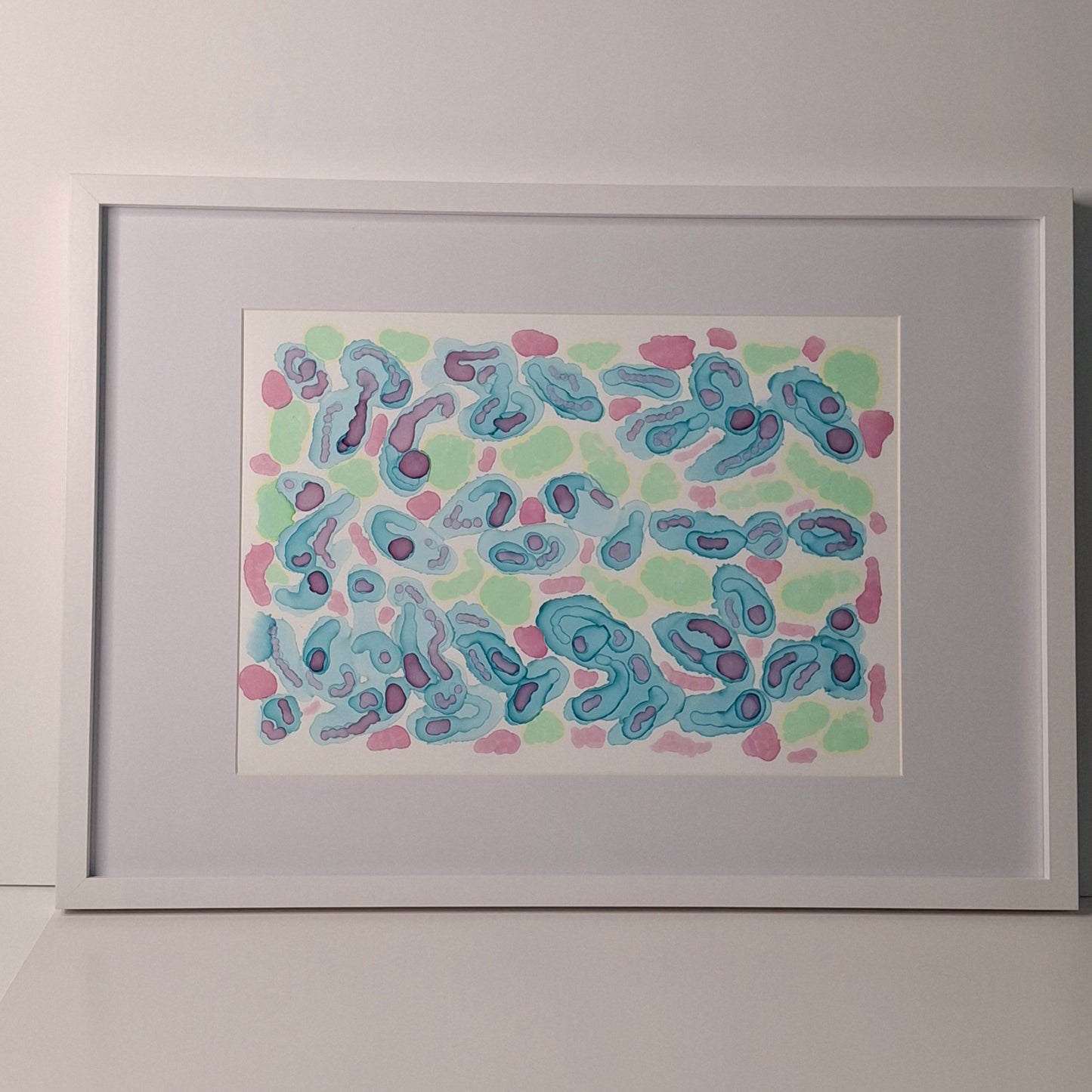 Framed abstract alcohol ink artwork in blue, green, and soft warm tones with organic circular shapes, titled “Tidepool Waltz” by Elizabeth Marshall.